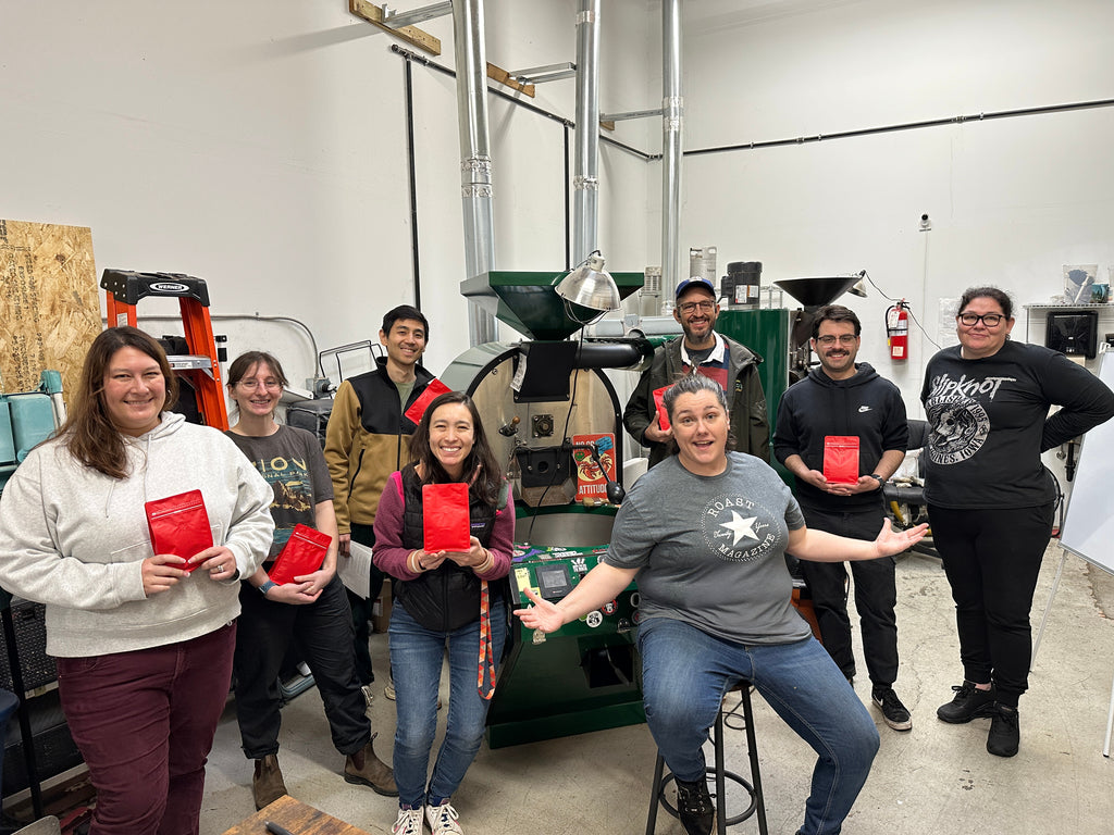 Group of people holding red bags in a coffee roastery